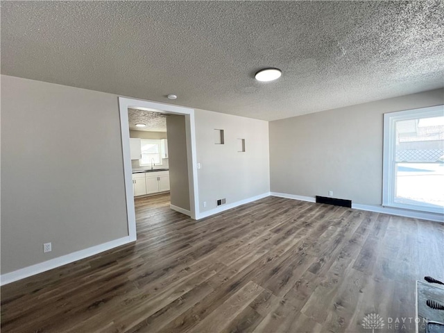 unfurnished room with baseboards, dark wood finished floors, and a textured ceiling