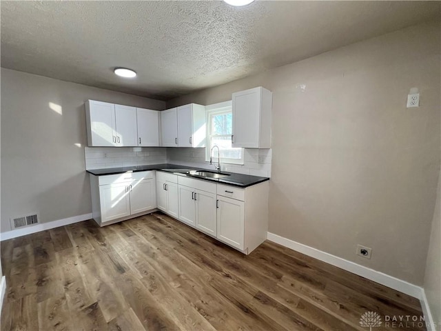 kitchen with dark countertops, white cabinets, and visible vents