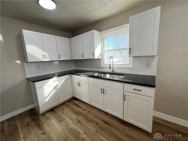 kitchen featuring dark countertops, a sink, and white cabinets