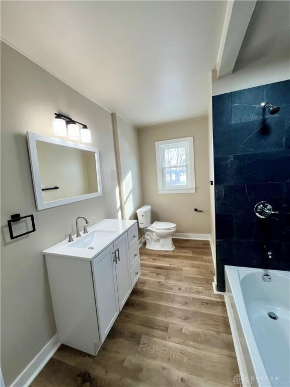 bathroom with toilet, wood finished floors, vanity, and baseboards