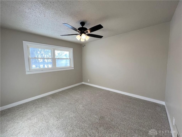 empty room featuring a textured ceiling, carpet floors, ceiling fan, and baseboards