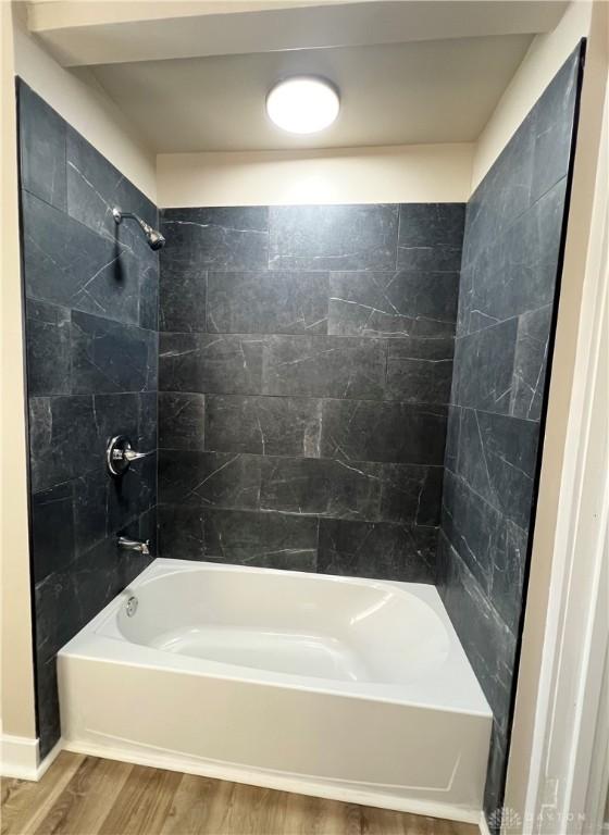 bathroom with washtub / shower combination and wood finished floors