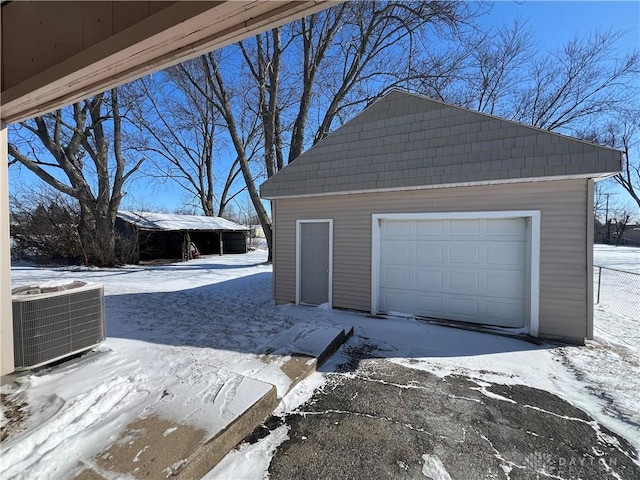 snow covered garage with a garage and cooling unit