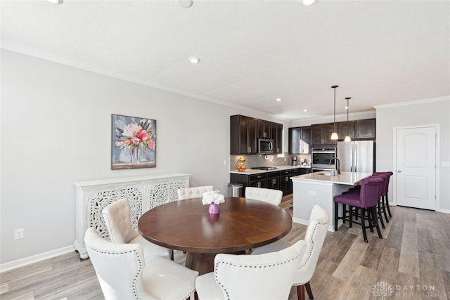 dining space with baseboards, recessed lighting, light wood-style flooring, and crown molding