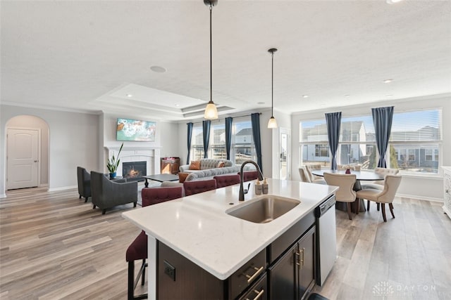 kitchen featuring decorative light fixtures, a sink, open floor plan, dishwasher, and a center island with sink