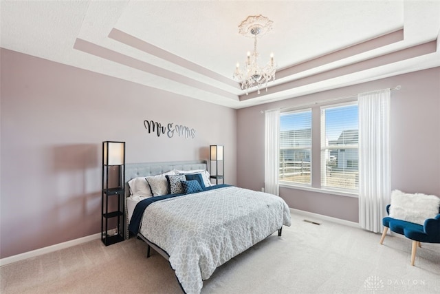 bedroom featuring a chandelier, a tray ceiling, carpet, and baseboards