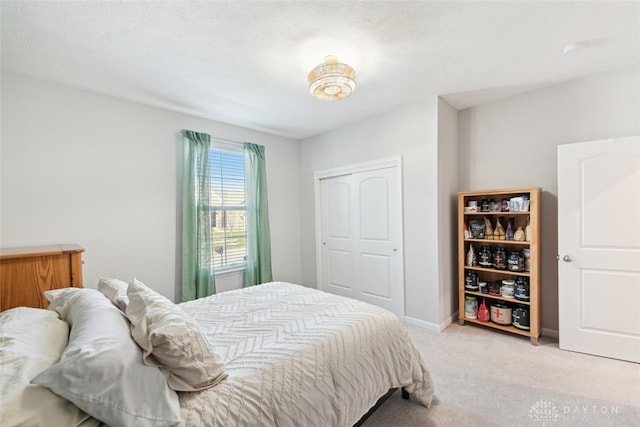 bedroom with baseboards, a closet, and light colored carpet