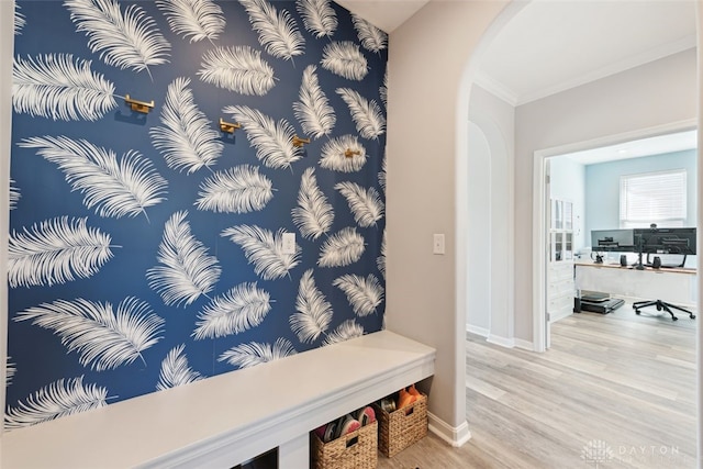 mudroom featuring arched walkways, ornamental molding, light wood-type flooring, and baseboards