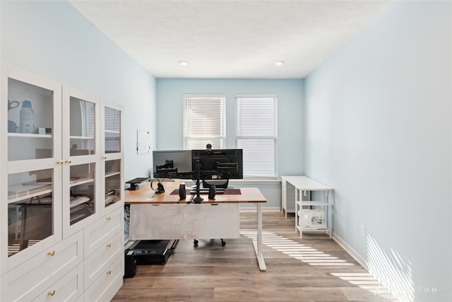 office space featuring baseboards, a textured ceiling, and light wood-style floors