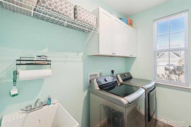 laundry area featuring washing machine and clothes dryer, a sink, cabinet space, and baseboards