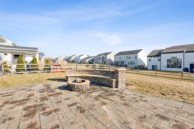 view of patio with a fire pit, fence, and a residential view