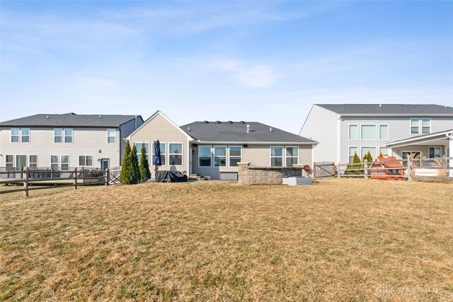 rear view of property with a lawn and fence