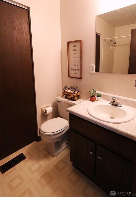 bathroom featuring toilet, a shower, visible vents, and vanity