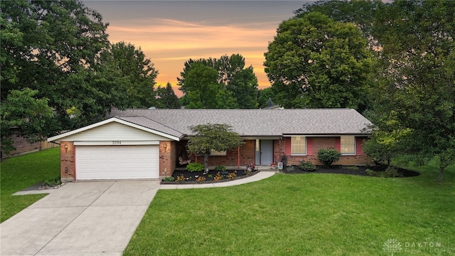 ranch-style house featuring brick siding, a yard, driveway, and an attached garage