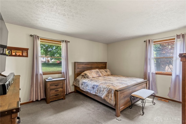 bedroom with carpet, visible vents, and a textured ceiling