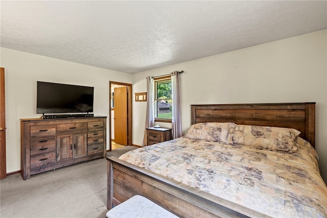 bedroom featuring light carpet, baseboards, and a textured ceiling