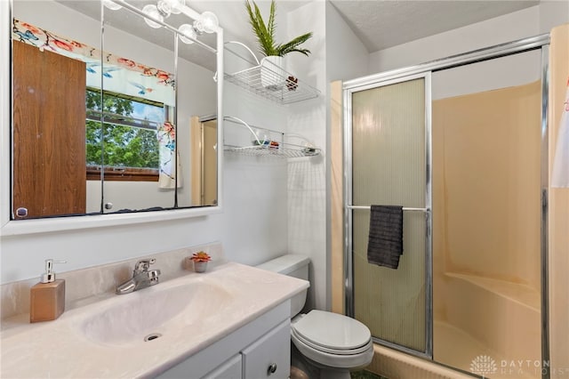 full bathroom featuring toilet, a shower stall, a textured ceiling, and vanity