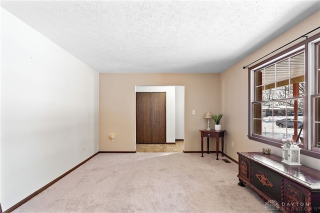 living area featuring baseboards, a textured ceiling, and light colored carpet