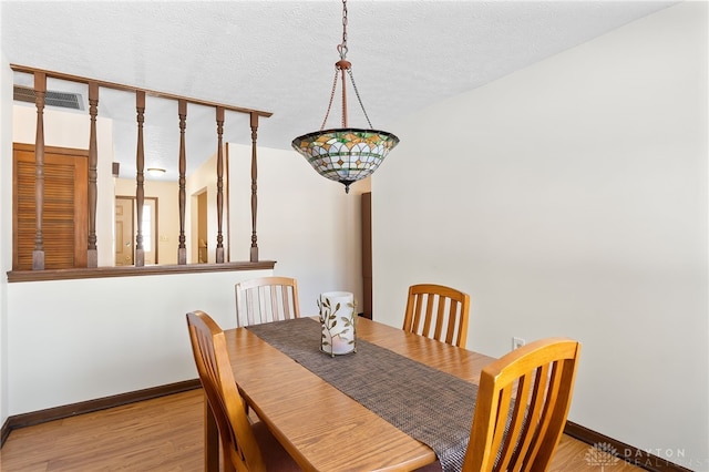 dining room with visible vents, a textured ceiling, light wood-style flooring, and baseboards