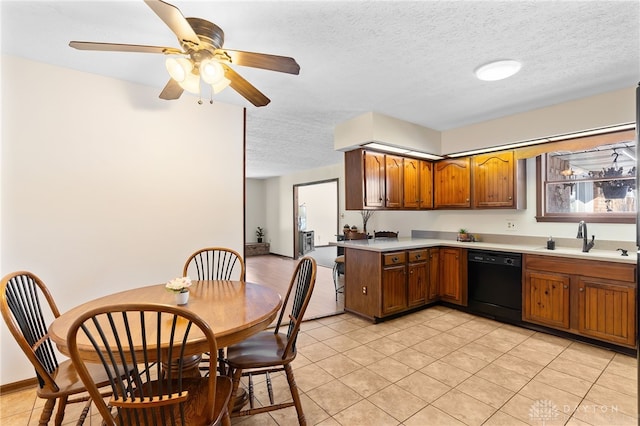 kitchen with a textured ceiling, a sink, black dishwasher, light countertops, and brown cabinetry