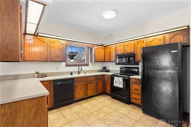 kitchen with a sink, black appliances, brown cabinetry, and light countertops