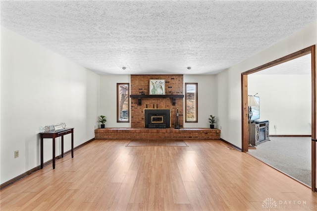 unfurnished living room with a fireplace, light wood-style flooring, and a textured ceiling