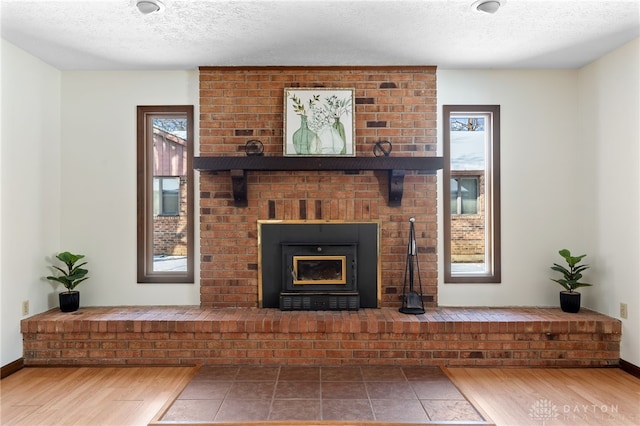 living area featuring a fireplace, baseboards, a textured ceiling, and wood finished floors