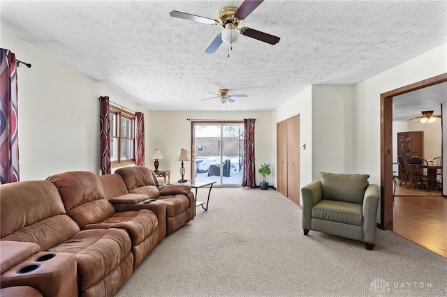 living room with light colored carpet, ceiling fan, and a textured ceiling