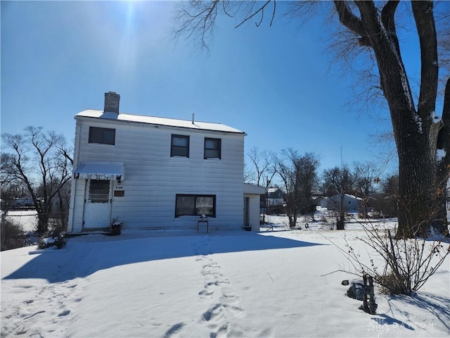 snow covered back of property featuring fence and a chimney