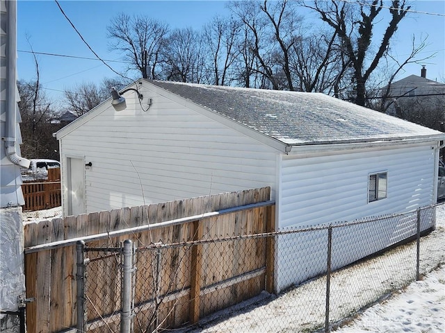 view of snowy exterior featuring a shingled roof and fence