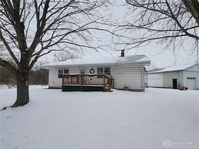 snow covered rear of property featuring a chimney and a deck