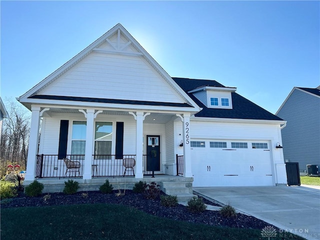 view of front of house with a garage, concrete driveway, a porch, and central AC