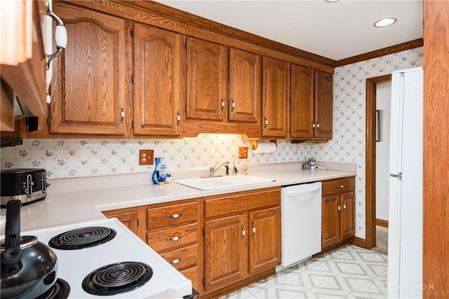 kitchen featuring brown cabinets, light countertops, a sink, white appliances, and wallpapered walls