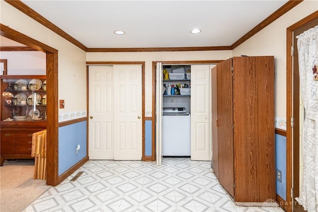 bedroom featuring multiple closets, washer / clothes dryer, crown molding, and light floors