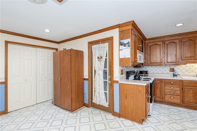 kitchen with light floors, light countertops, electric range, white microwave, and brown cabinetry