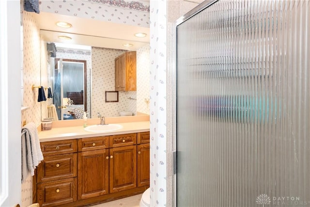 bathroom featuring a stall shower, vanity, and wallpapered walls