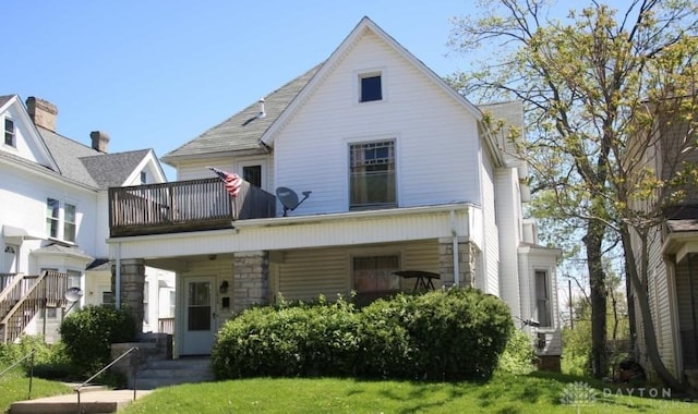 back of house with a porch, a lawn, and a balcony