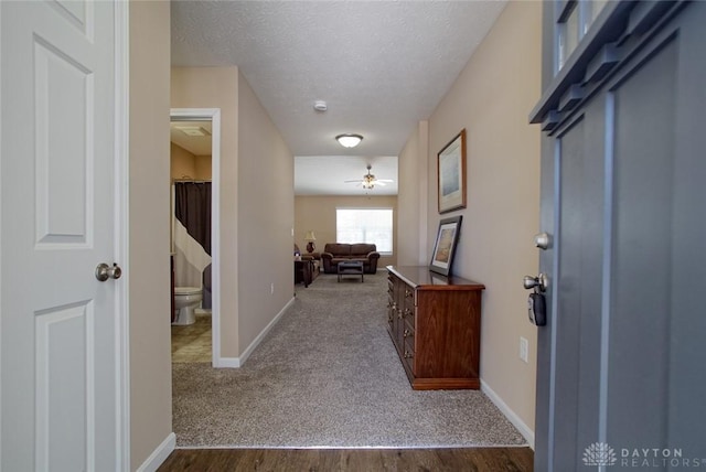 foyer featuring baseboards, dark colored carpet, and a textured ceiling