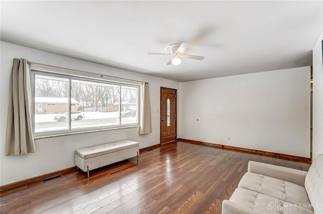 foyer entrance featuring dark wood-type flooring, a ceiling fan, visible vents, and baseboards