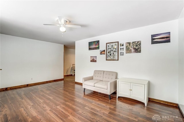 living area with dark wood-type flooring, baseboards, and a ceiling fan