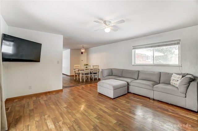 unfurnished living room featuring dark wood-type flooring, a ceiling fan, and baseboards