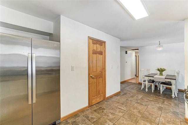 kitchen featuring freestanding refrigerator, decorative light fixtures, and baseboards