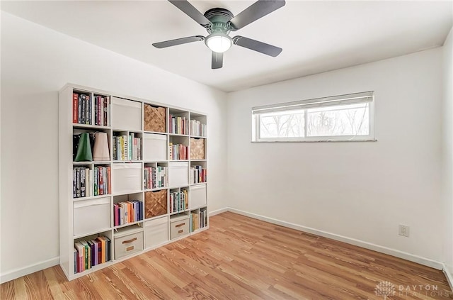 unfurnished room with wood finished floors, a ceiling fan, and baseboards