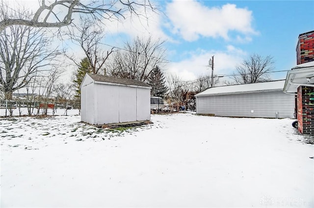 yard covered in snow featuring fence, a storage unit, and an outdoor structure