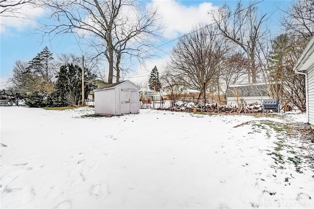 yard covered in snow with a storage shed and an outbuilding