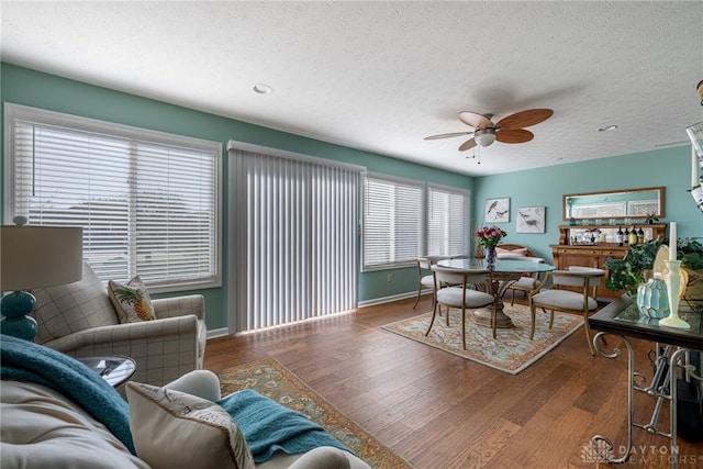 dining area with a textured ceiling, ceiling fan, dark wood finished floors, and baseboards