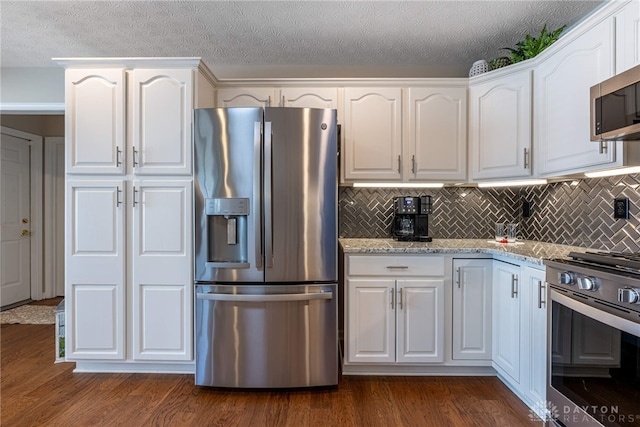 kitchen with light stone countertops, white cabinetry, and appliances with stainless steel finishes