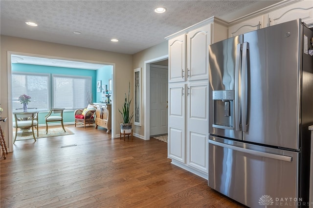 kitchen featuring a textured ceiling, recessed lighting, wood finished floors, white cabinetry, and stainless steel refrigerator with ice dispenser