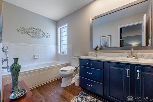 full bath with toilet, a garden tub, wood finished floors, and vanity