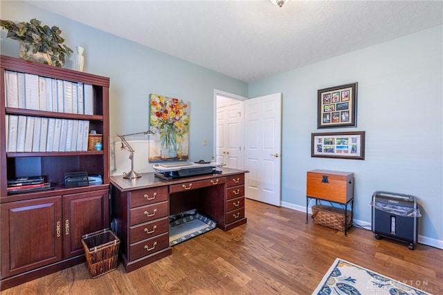 home office with dark wood-style floors, a textured ceiling, and baseboards